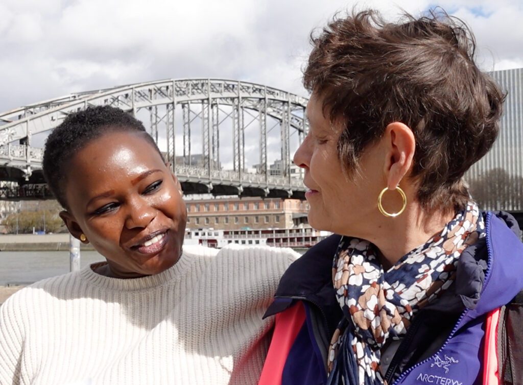 Une femme noire échange un sourire complice avec une femme blanche